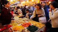 Orang-orang mencicipi makanan ringan saat berbelanja persiapan Tahun Baru Imlek di pasar Dihua Street di Taipei, Selasa (29/1). Warga Taiwan mulai berburu makanan lezat, kue kering dan barang- lainnya di pasar menjelang Imlek. (AP/Chiang Ying-ying)