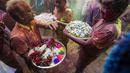Umat Hindu dengan persembahan berjalan menuju mobil yang membawa patung dewa Krishna selama festival Holi di Kolkata, India, Minggu, 5 Maret 2023. Holi merupakan selebrasi adat umat Hindu India yang menjadi festival paling dinanti para pelancong mancanegara ketika berkunjung ke India. .(AP Photo/Bikas Das)
