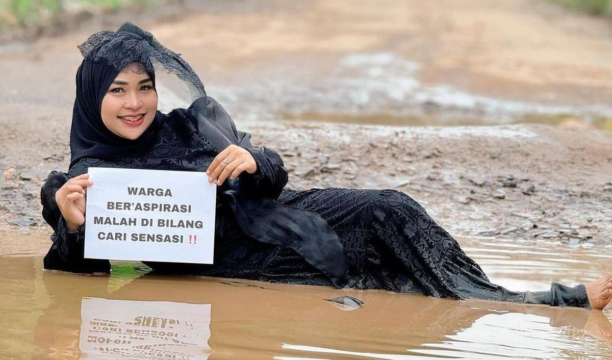 Dalam unggahan yang dibagikan pada 3 Mei 2024, Ummu Hani terlihat berpose dan bahkan "berenang" di dalam lubang jalan rusak.