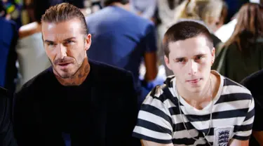 Mantan pesepakbola, David Beckham dan putranya Brooklyn tampak duduk di barisan depan fashion show koleksi musim panas 2018 Victoria Beckham dalam pagelaran New York fashion Week, Minggu (10/9). (EDUARDO MUNOZ ALVAREZ / AFP)