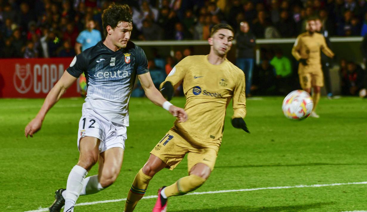Pemain Ceuta, Juan Gutierrez, berebut bola dengan pemain Barcelona, Ferran Torres, pada laga Copa del Rey di Stadion Alfonso Murube (19/1/2023). Bertanding di Stadion Alfonso Murube pada Jumat (20/1/2023), Barcelona sukses menumbangkan Ceuta dengan skor 5-0. (AP Photo/Antonio Sempere)