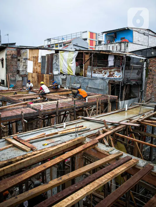 Para pekerja menyelesaikan pembangunan rumah panggung di dekat bantaran Kali Ciliwung, Kampung Melayu, Jakarta, Rabu (7/4/2021). Pemerintah Provinsi DKI Jakarta melakukan renovasi terhadap 40 hunian warga Kampung Melayu menjadi rumah panggung. (Liputan6.com/Faizal Fanani)