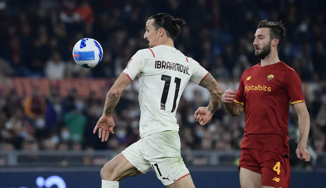 Penyerang AC Milan, Zlatan Ibrahimovic (kiri) dan pemain tengah AS Roma, Bryan Christante mengincar bola pada pekan ke-11 Liga Italia di Stadio Olimpico, Roma, Senin (1/11/2021) dini hari WIB. AC Milan menang 2-1 meski harus bermain 10 orang. (Filippo MONTEFORTE / AFP)