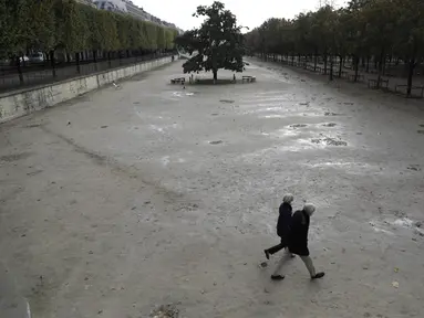 Orang-orang berjalan di taman Tuileries yang kosong di Paris (14/10/2020). Presiden Prancis Emmanuel Macron memberikan wawancara televisi nasional Rabu malam untuk berbicara tentang virus, yang pertama dalam beberapa bulan. (AP Photo/Lewis Joly)