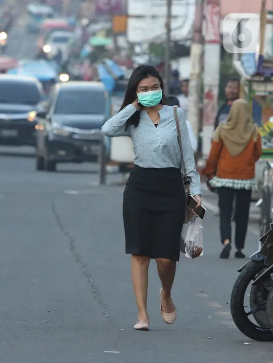 Warga mengenakan masker berjalan di Depok, Jawa Barat, Senin (2/3/2020). Dua pasien terjangkit corona yang dirawat di RSPI Sulyanti Saroso  merupakan warga Depok. Mendengar kabar yang diumumkan Presiden Jokowi membuat warga mulai mengantisipasi mengenakan masker. (Liputan6.com/Herman Zakharia)