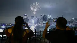 Warga mengambil gambar kembang api yang menghiasi langit kota New York saat perayaan hari kemerdekaan Amerika Serikat (AS) , Senin (4/7). AS merayakan hari ulang tahun kemerdekaan yang ke-240 dari Inggris. (KENA Betancur/AFP)