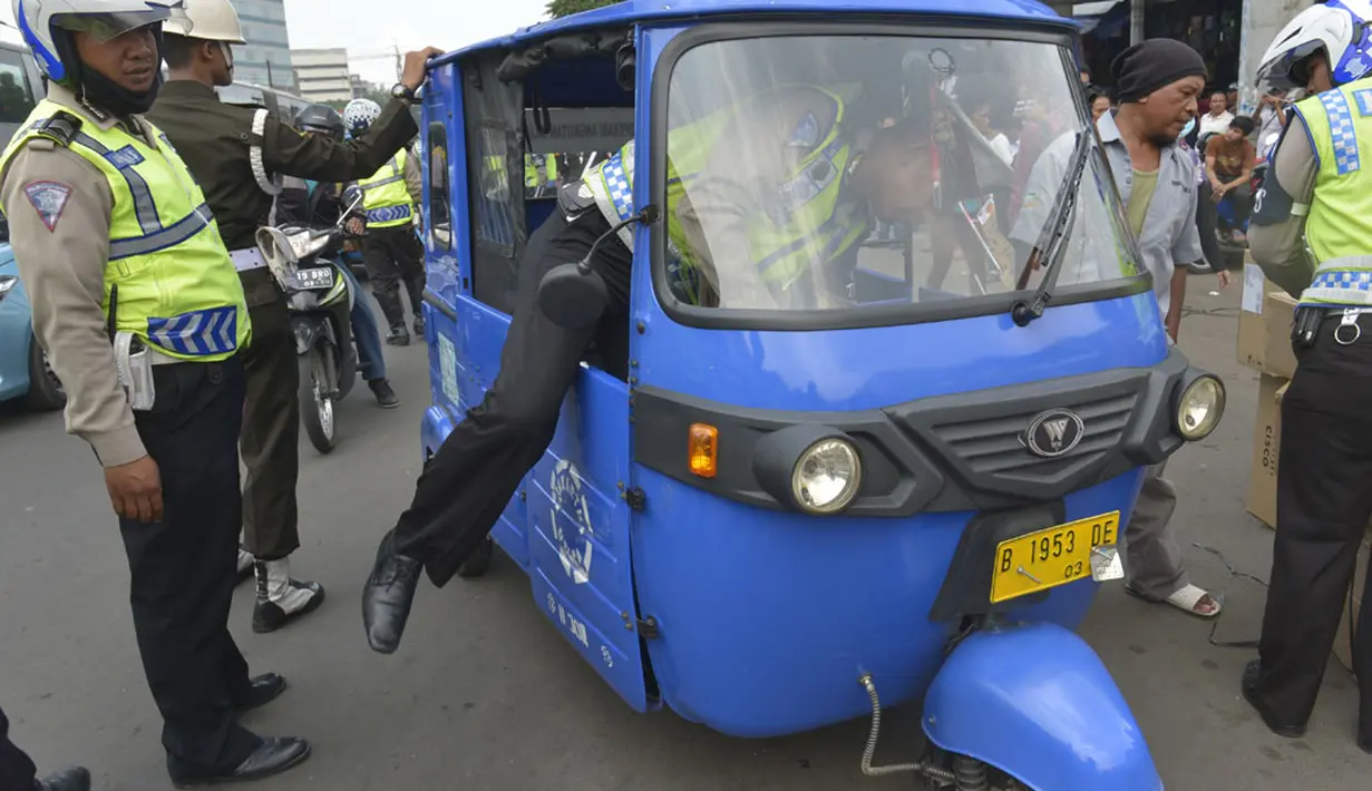 Polisi berusaha mengendarai bajaj yang terkena razia ketika digelar Operasi Zebra 2014 di sekitar Pasar Senen, Jakarta, Rabu (26/11). (ANTARA FOTO/Saptono)