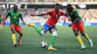 Penyerang Gambia Muhammed Badamosi bersaing dengan pemain Kamerun Nouhou Tolo dan Michael Ngadeu-Ngadjui pada pertandingan perempatfinal Piala Afrika 2021 di Japoma Stadium, Minggu (30/1/2022) dini hari WIB. Kamerun melangkah ke semifinal usai menang atas Gambia, 2-0. (CHARLY TRIBALLEAU / AFP)