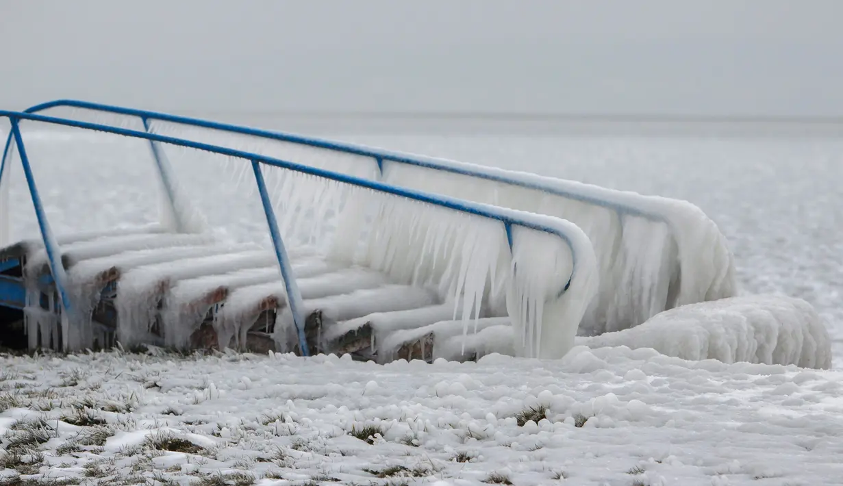 Sebuah tangga tertutup salju di pantai Danau Balaton di Fonyod, Hungaria (26/2). Cuaca ekstrem dengan angin kencang melanda sebagian besar wilayah Hungaria. (Gyorgy Varga / MTI via AP)