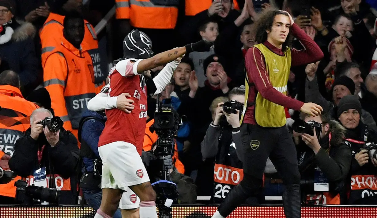 Striker Arsenal Pierre-Emerick Aubameyang (kiri) mengenakan topeng superhero Black Panther usai mencetak gol ke gawang Stade Rennes pada leg kedua babak 16 besar Liga Europa di Stadion Emirates, London, Inggris  (14/3). (Reuters/Tony O'Brien)