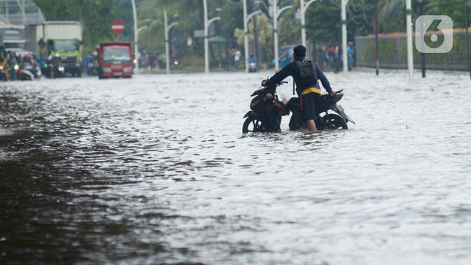 Pengendara mendorong sepeda motor mereka saat melewati banjir yang merendam Jalan Ahmad Yani, Jakarta, Sabtu (8/2/2020). Hujan yang mengguyur Jakarta sejak semalam membuat sejumlah ruas jalan terendam banjir. (merdeka.com/Imam Buhori)