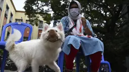 Seorang wanita menunggu dokter hewan untuk menyuntik anjing peliharaannya dengan dosis vaksin antirabies pada kesempatan Hari Rabies Sedunia di Rumah Sakit Universitas Hewan Tamil Nadu, Chennai, Rabu (29/9/2021). Hari Rabies Sedunia diselenggarakan pada 28 September setiap tahun. (Arun SANKAR/AFP)