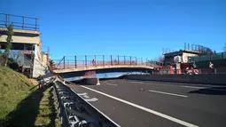 Petugas pemadam kebakaran berusaha mengevakuasi jembatan roboh di Ancona yang melintang di atas ruas jalan tol di wilayah pesisir pantai Italia, Kamis (9/3). Jembatan tersebut diketahui sedang dalam pekerjaan pelebaran. (ANSA via AP)