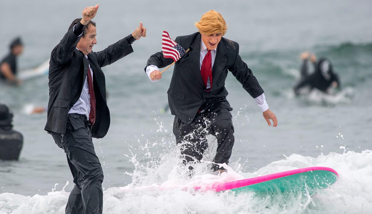 Gary Crane berselancar mengenakan kostum menyerupai Presiden AS, Donald Trump di Newport Beach, California, 28 Oktober 2017. Acara ini untuk merayakan Halloween yang jatuh pada tanggal 31 Oktober. (Paul Rodriguez/The Orange County Register via AP)