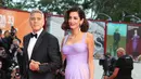Pasangan selebritis, George dan Amal Clooney berpose untuk fotografer setibanya di Venice Film Festival ke-74, Italia, 2 September 2017. Di momen itu, Amal menebar pesonanya dalam balutan gaun sutra panjang koleksi Versace. (AP Photo/Domenico Stinellis)