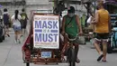 Seorang pria mengendarai becaknya dengan slogan untuk mengingatkan orang agar memakai masker untuk mencegah penyebaran virus corona di Manila, Filipina, Senin (26/4/2021). Infeksi COVID-19 di Filipina melonjak melewati 1 juta pada hari Senin dalam tonggak suram terbaru. (AP Photo/Aaron Favila)