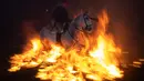 Penunggang kuda melompati api unggun selama festival Luminarias di San Bartolome de Pinares, Spanyol, Rabu (16/1). Penduduk desa ini menegaskan tidak pernah ada warga maupun binatang yang terluka sepanjang festival diadakan. (GABRIEL BOUYS / AFP)