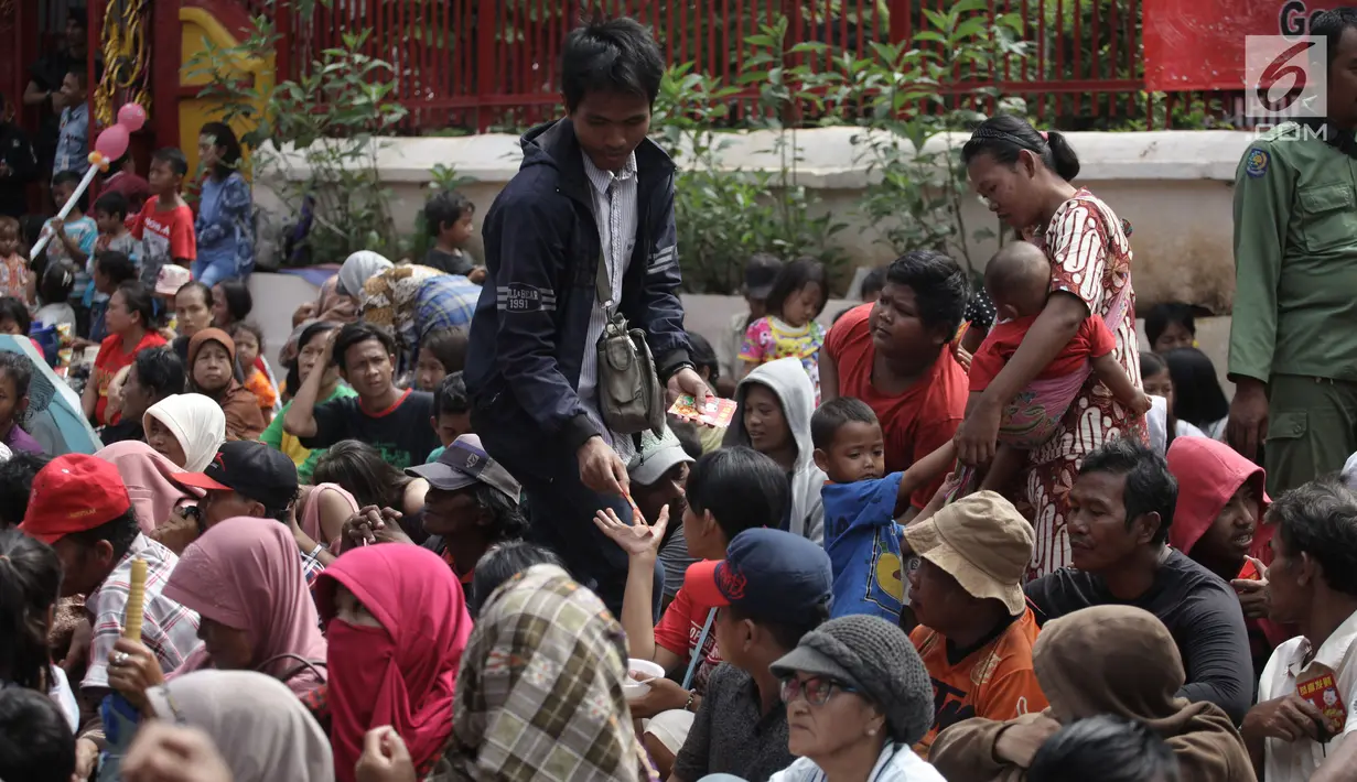 Seorang warga membagikan angpau kepada pengemis di Wihara Dharma Bhakti, Petak Sembilan, Jakarta Barat, Jumat (16/2). Dalam perayaan Tahun Baru Imlek, pembagian Angpao ini biasa dilakukan warga Tionghoa untuk berbagi rezeki. (Liputan6.com/Arya Manggala)