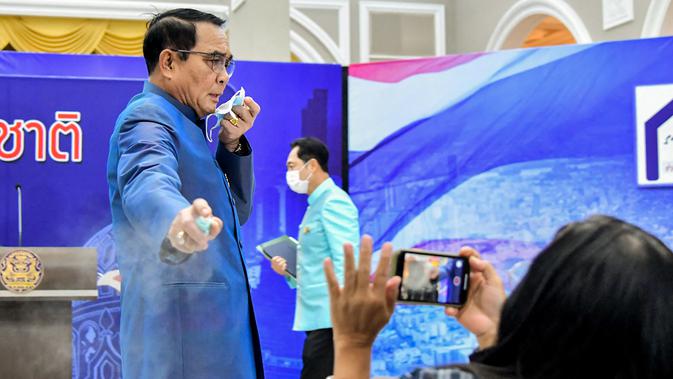 Perdana Menteri (PM) Thailand, Prayuth Chan-ocha menyemprotkan pembersih tangan ke barisan depan wartawan dalam konferensi pers di Bangkok, Selasa (9/3/2021). Hal Itu dilakukan Prayuth dalam upaya untuk menghindari pertanyaan tentang perombakan kabinet. (HO/ROYAL THAI GOVERNMENT/AFP)