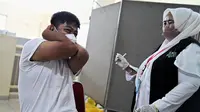 Reaksi seorang siswa SMA saat menerima dosis vaksin virus corona COVID-19 Pfizer di Rumah Sakit Zainoel Abidin, Banda Aceh, Aceh, Selasa (9/11/2021). Vaksinasi COVID-19 di kalangan warga Kota Banda Aceh tembus 80 persen. (CHAIDEER MAHYUDDIN/AFP)