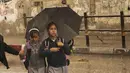 Gadis-gadis sekolah menutupi diri dengan payung dari hujan dalam perjalanan pulang ke rumah di Kota Gaza, Selasa (8/11/2022). Hujan deras menyebabkan banjir bandang di Jalur Gaza pada hari Selasa, di mana infrastruktur yang bobrok sering membuat air banjir tidak surut, memperpanjang kerusakan. (AP Photo/Adel Hana)