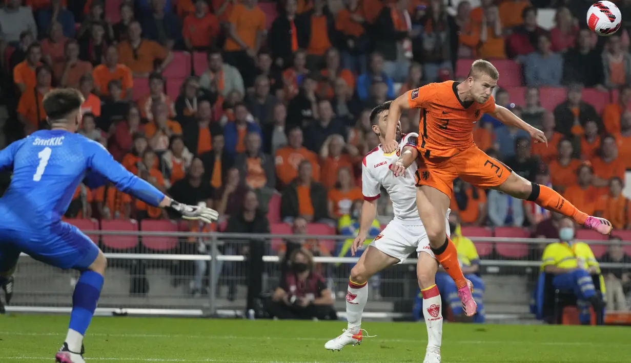 Bek timnas Belanda, Matthijs de Ligt menyundul bola saat kiper Montenegro Matija Sarkic mencoba menghalau pada laga lanjutan kualifikasi Piala Dunia 2022 di Stadion Phillips, Minggu (5/8/2021) dini hari WIB. Belanda sukses menghantam Montenegro dengan skor 4-0. (AP Photo/Peter Dejong)