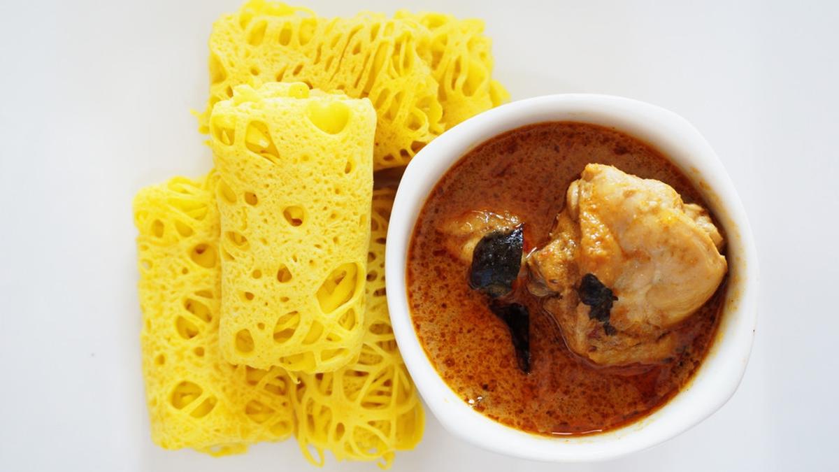 Roti Jala yang digulung rapi, siap disajikan bersama kuah kari yang menggugah selera, mencerminkan warisan kuliner Melayu yang kaya dan penuh cita rasa
