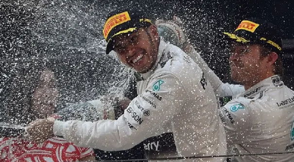 Nico Rosberg membalas menyemprotkan sampanye ke muka Lewis Hamilton