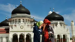 Turis asing mengenakan jilbab saat mengunjungi Masjid Agung Baiturrahman di Banda Aceh, Aceh pada 6 Agustus 2019. Selain sebagai tempat ibadah, Masjid Baiturahman juga menjadi tempat wisata bagi turis lokal dan mancanegara. (CHAIDEER MAHYUDDIN / AFP)
