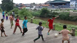 Anak-anak bermain sepak bola di jalur inspeksi Sungai Ciliwung di kawasan Rawajati, Jakarta, Rabu (23/1). Keterbatasan lahan tidak menyurutkan semangat mereka untuk bermain sepak bola meski di tempat seadanya. (Liputan6.com/Immanuel Antonius)