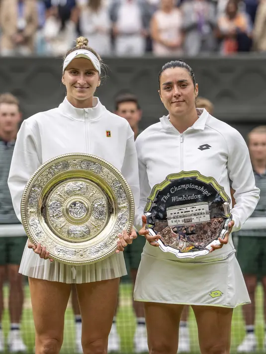 Marketa Vondrousova dari Republik Ceko (kiri) memegang Venus Rosewater Dish bersama Ons Jabeur dari Tunisia yang memegang trofi runner up, saat upacara penyerahan final tunggal putri pada hari ketiga belas kejuaraan tenis Wimbledon di London, Sabtu, 15 Juli 2023. (Andrew Baker/Pool Photo via AP)