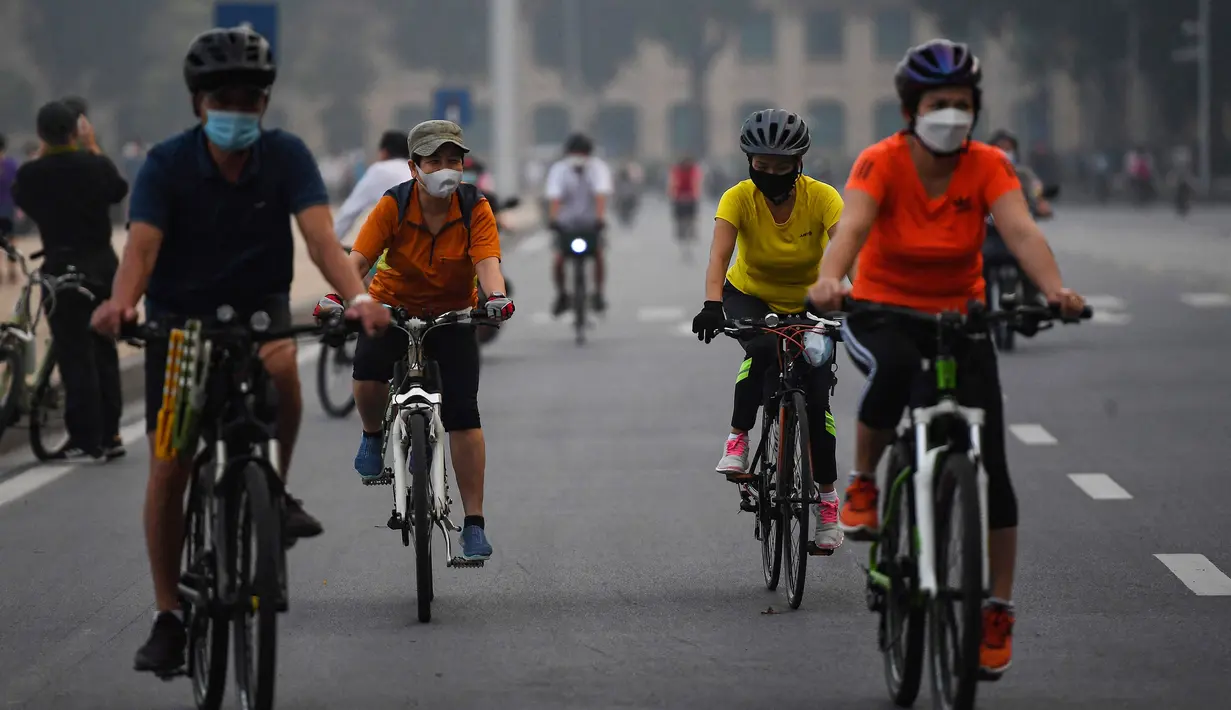 Orang-orang mengendarai sepeda di sepanjang jalan di Hanoi setelah otoritas kota mengizinkan kegiatan olahraga menyusul pelonggaran pembatasan Covid-19, Selasa (28/9/2021). Sejauh ini, 94 persen dari populasi orang dewasa Hanoi telah menerima satu suntikan vaksin COVID-19. (Nhac NGUYEN/AFP)