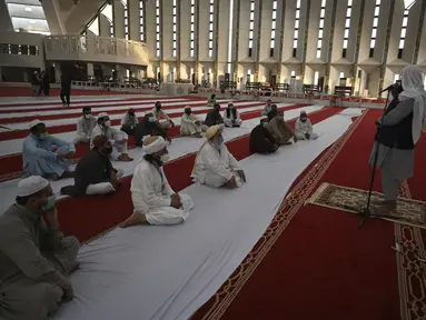 Umat Muslim mendengarkan Imam (kanan) di Masjid Agung Faisal di awal Itikaf, di sebuah masjid untuk pria selama bulan suci Ramadhan di Islamabad (3/5/2021). Umat Muslim melakukan Itikaf 10 hari terakhir bulan Ramadhan, dalam rangka meraih malam kemuliaan atau Lailatul Qadar. (AFP/Aamir Qureshi)