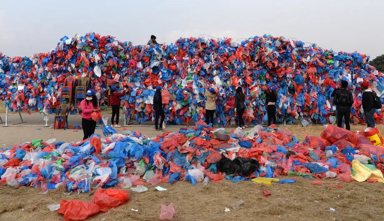 Relawan Nepal dan siswa sekolah membuat replika Laut Mati dari plastik daur ulang di Kathmandu pada 5 Desember 2018. Sebanyak 100.000 kantong plastik diikat di atas kisi besi dengan lebar 20 meter dan tinggi 5 meter. (PRAKASH MATHEMA / AFP)