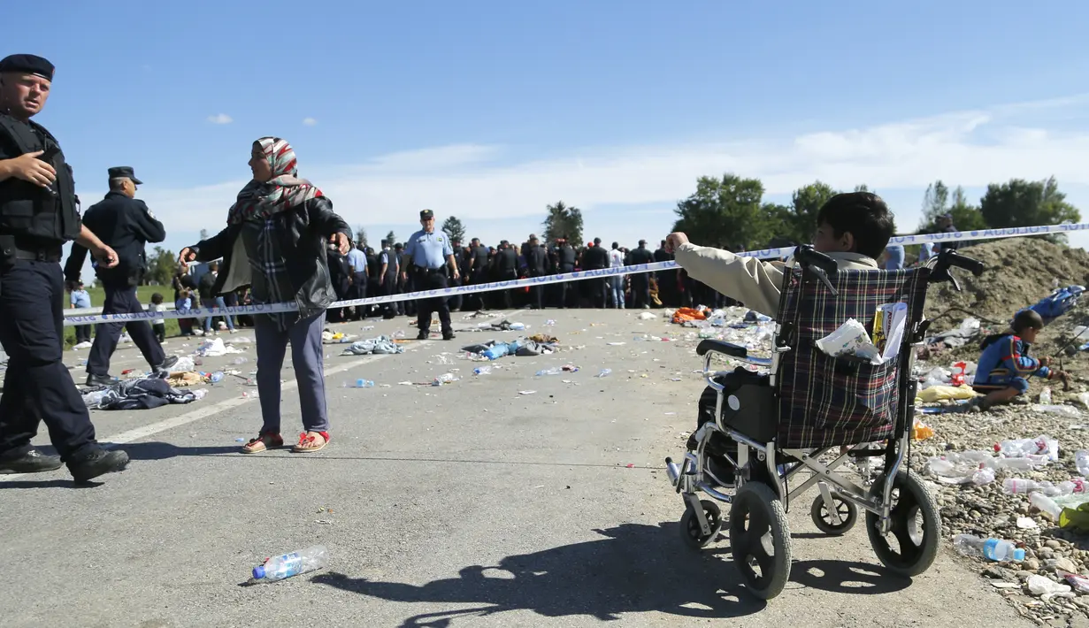 Seorang polisi mendekati anak imigran berkursi roda di perbatasan antara Serbia dan Kroasia di dekat Tovarnik, Kroasia (21/9/2015). (REUTERS / Antonio Bronic)