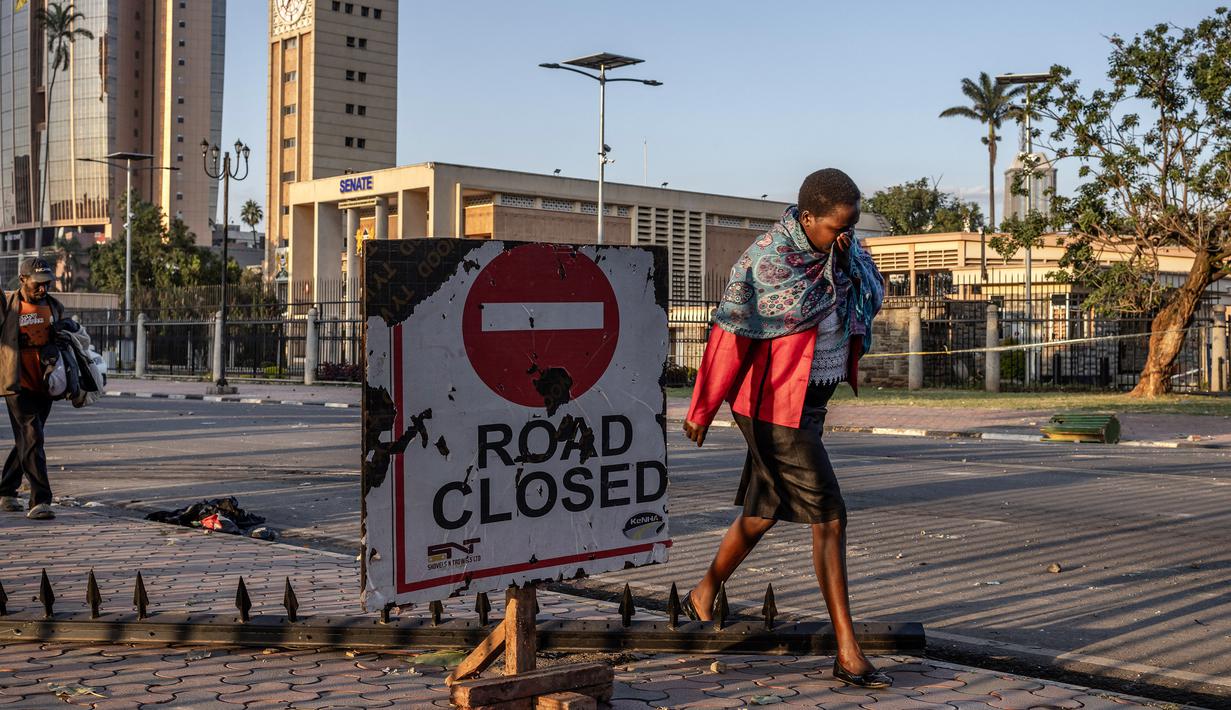 Seorang wanita menutupi wajahnya ketika sisa-sisa gas air mata terasa di udara saat berjalan melewati gedung Parlemen Kenya di pusat kota Nairobi, pada 26 Juni 2024. (LUIS TATO/AFP)