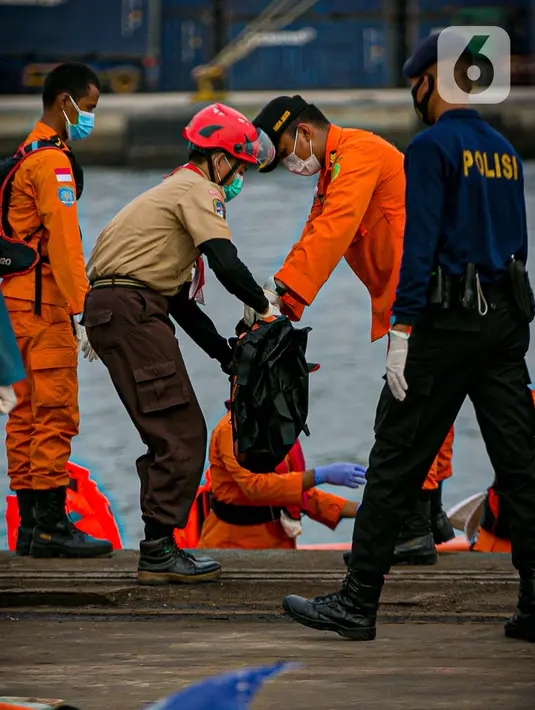 Petugas membawa body part dari kapal Basarnas di JICT II Tanjung Priok, Jakarta, Jumat (15/1/2021). 13 kantong yang dibawa ini berisi bagian tubuh penumpang (body part) Sriwijaya Air SJ182. (Liputan.com/Faizal Fanani)