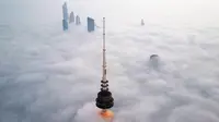 Foto udara memperlihatkan pemandangan Liberation Tower (depan) di tengah kabut tebal, Kuwait City, 21 Januari 2023. Liberation Tower adalah menara telekomunikasi setinggi 372 meter atau 1.220 kaki yang menjadi bangunan tertinggi kedua di Kuwait dan bangunan tertinggi ke-39 di dunia. (YASSER AL-ZAYYAT/AFP)