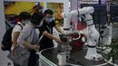 Seorang peserta pameran mendemonstrasikan robot industri buatan China kepada pengunjung di Konferensi Robot Dunia di Pusat Konferensi dan Pameran Internasional Yichuang di Beijing, Kamis (18/8/2022). (AP Photo/Andy Wong)