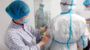 Petugas medis Rumah Sakit Afiliasi Universitas Qingdao memeriksa baju pelindung rekannya di Rumah Sakit Tongji cabang Guanggu di Wuhan, 20 Februari 2020. Beberapa langkah pencegahan dilakukan secara ketat selama dan sesudah jam kerja oleh pekerja medis untuk melawan virus corona. (Xinhua/Cai Yang)