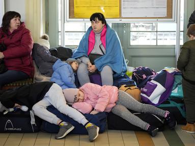 Anak-anak dari Ukraina tidur di stasiun kereta api di Przemysl, Polandia tenggara, pada Rabu (23/3/2022). Polandia telah menerima lebih dari 2 juta pengungsi Ukraina sejak invasi Rusia pada 24 Februari lalu. (AP Photo/Sergei Grits)