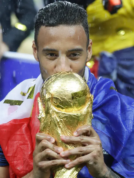 Pemain timnas Prancis, Corentin Tolisso mencium trofi Piala Dunia 2018 saat merayakan gelar juara setelah mengalahkan Kroasia pada  laga final di Luzhniki Stadium, Minggu (15/7). Prancis membekuk Kroasia dengan skor akhir 4-2. (AP Photo/Matthias Schrader)