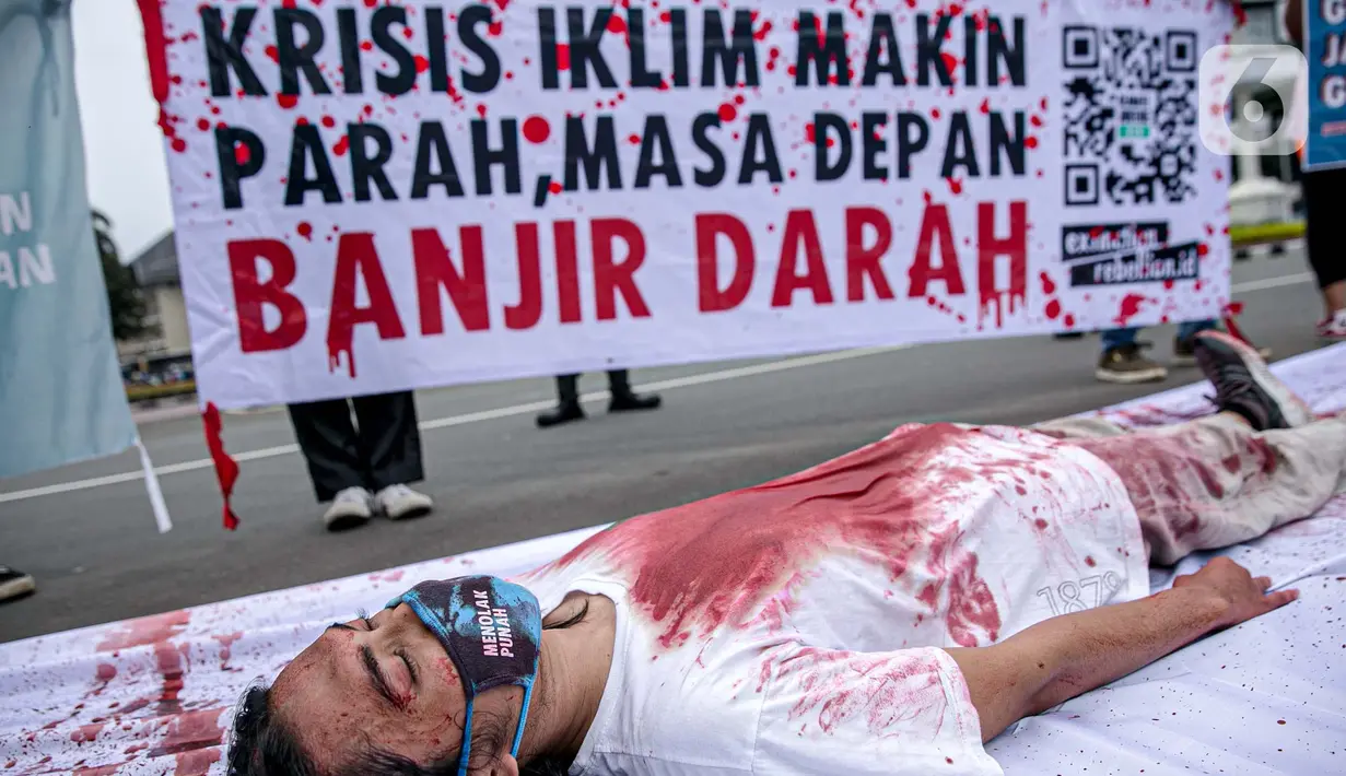 Aktivis melakukan teatrikal dengan menyiramkan darah di tubuhnya saat aksi serentak desak Presiden Jokowi deklarasikan Darurat Iklim di kawasan Patung Kuda, Jakarta, Jumat (19/3/2021). Aksi serentak di beberapa lokasi itu untuk menuntut deklarasi darurat iklim. (Liputan6.com/Faizal Fanani)