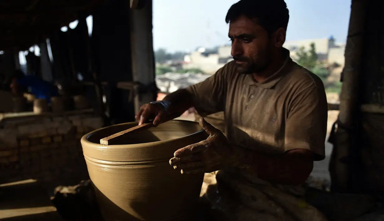 Seorang pembuat tembikar membuat pot tanah liat di sebuah bengkel di Karachi, Pakistan, Rabu (23/2/2022). (Rizwan TABASSUM/AFP)