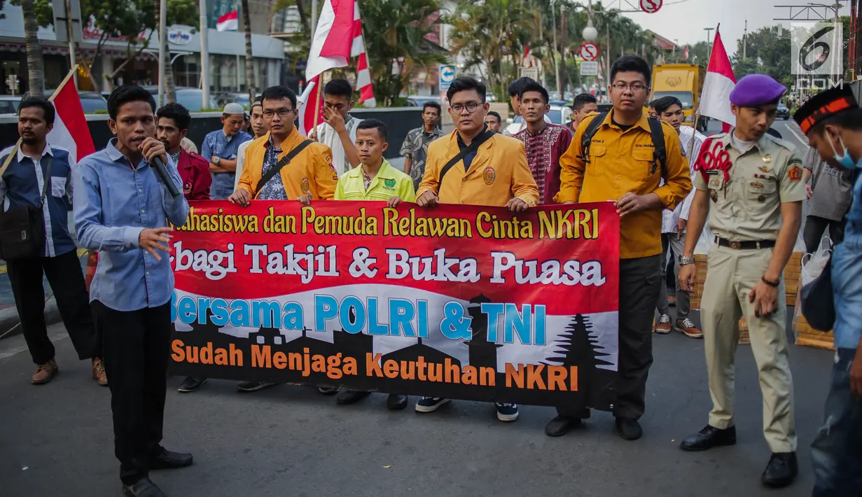 Peserta aksi yang tergabung dalam Mahasiswa dan Pemuda Relawan Cinta NKRI membagikan takjil ke anggota Polri yang bertugas di Gedung Bawaslu RI, Jakarta, Minggu (26/5). Aksi simpatik sebagai wujud apresiasi kepada anggota Polri-TNI yang menjaga keamanan aksi 22 Mei 2019. (Liputan6.com/Faizal Fanani)