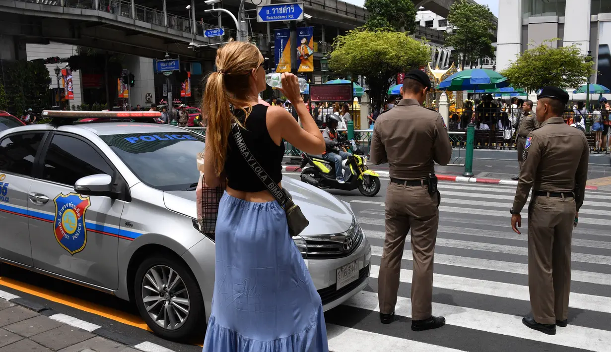 Seorang wanita menunggu untuk menyeberang jalan ke Kuil Erawan di Bangkok  (2/8/2019). Sedikitnya ada lima lokasi atau titik ledakan. Seperti di bawah halte BTS (Bangkok Sky Train) Chong Nonsi, persimpangan 57/1 Jalan Rama IX. (AFP Photo/Mladen Antonov)