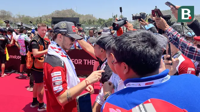 Pembalap Ducati Lenovo Team, Francesco Bagnaia (kiri), berbincang dengan penggemar yang hadir di Sirkuit Mandalika, Lombok , Minggu (15/10/2023). (Bola.com/Benediktus Gerendo Pradigdo)