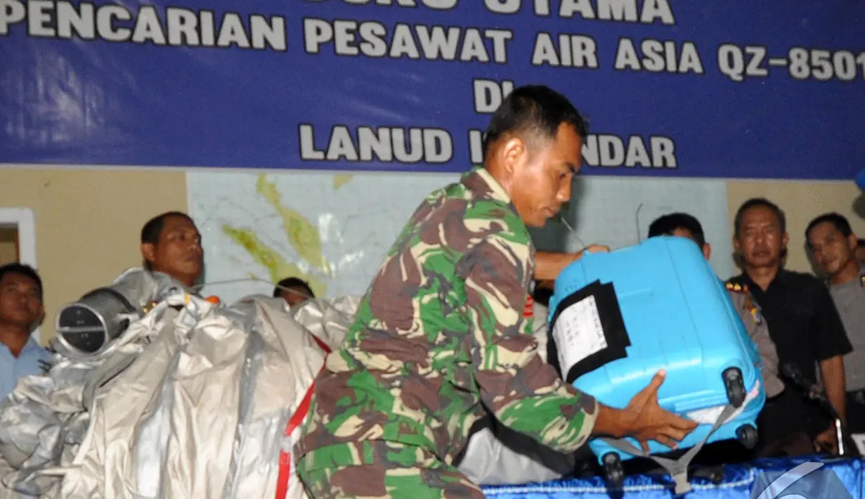 Salah satu anggota TNI memperlihatkan barang yang diduga milik penumpang pesawat AirAsia QZ8501, Pangkalan Bun, Kalteng, Selasa (30/12/2014). (Liputan6.com/Miftahul Hayat)