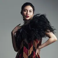 Ariel Tatum dengan dress megah bernuansa merah dan aksen bulu hitam di bagian dada. Dressnya ini memiliki detail asimetris yang menambah kesan edgy pada keseluruhan penampilannya. [Foto: Instagram/arieltatum]