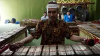 Rasino penyandang tuna netra yang menjadi guru gamelan di SMKN 8 Surakarta sedang memainkan instrumen gender.(Liputan6.com/Fajar Abrori)